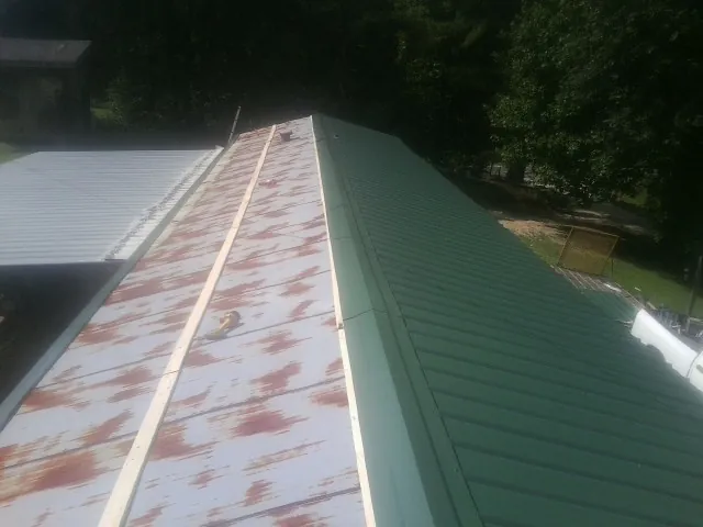 Old rusted panels beside newly installed green metal roofing — Wind Damage Roof Repair by Roofing Brothers in Fort Loudon