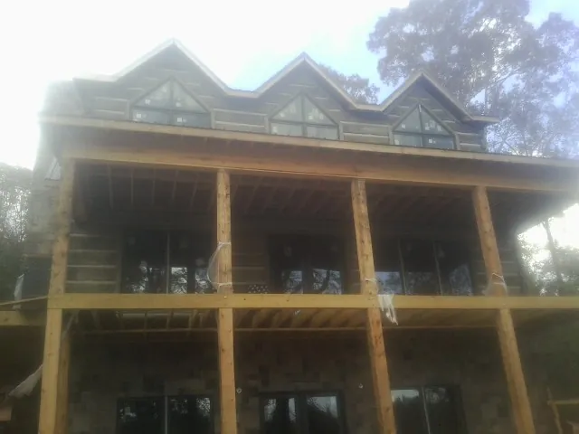 Dormers and porch framing on a large log home under construction — Roof Coating work by our crew in Fort Loudon