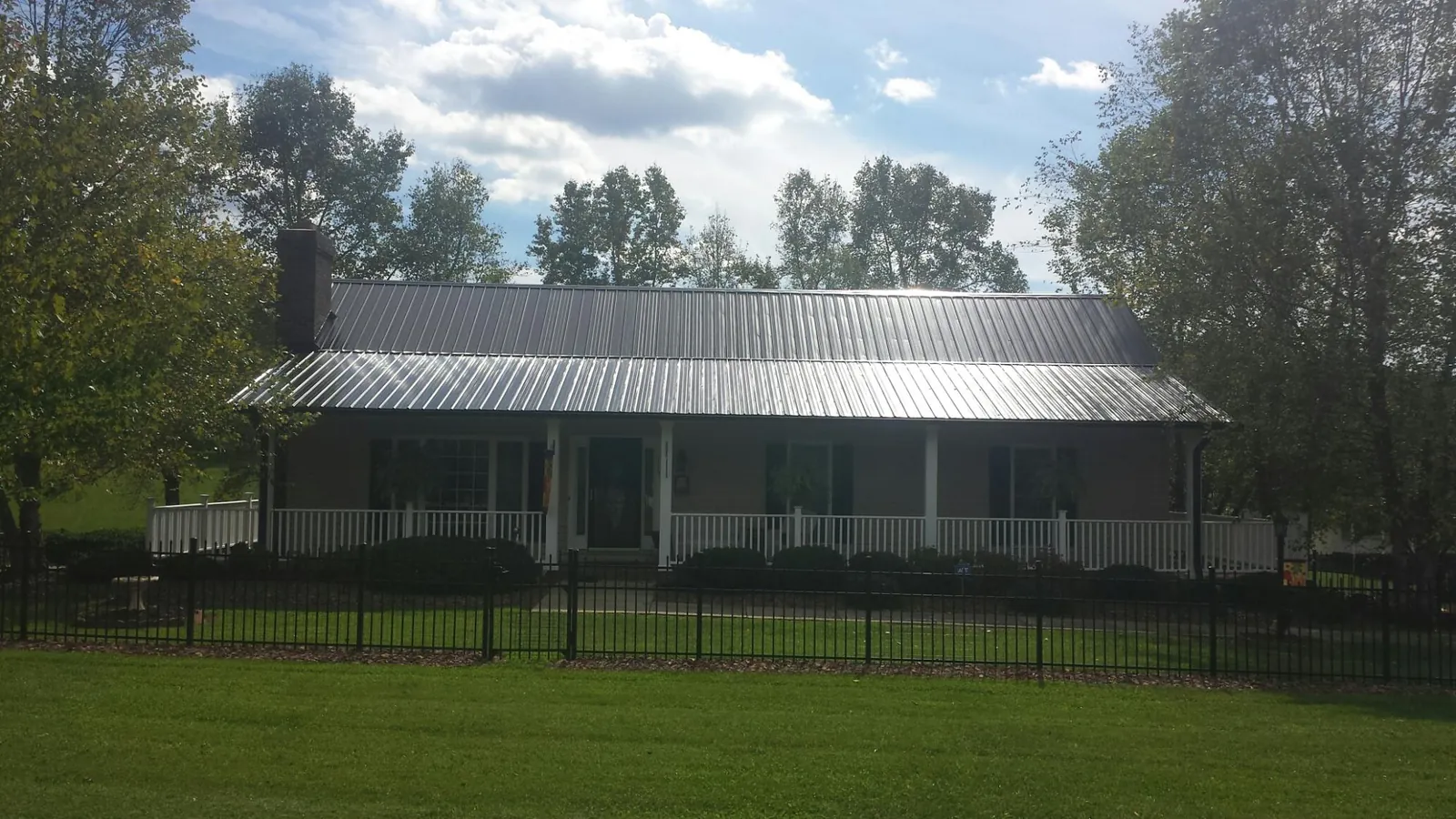 Gray metal roof on a brick ranch with a full width front porch — Gutter Guard Installation work by our crew in Fort Loudon