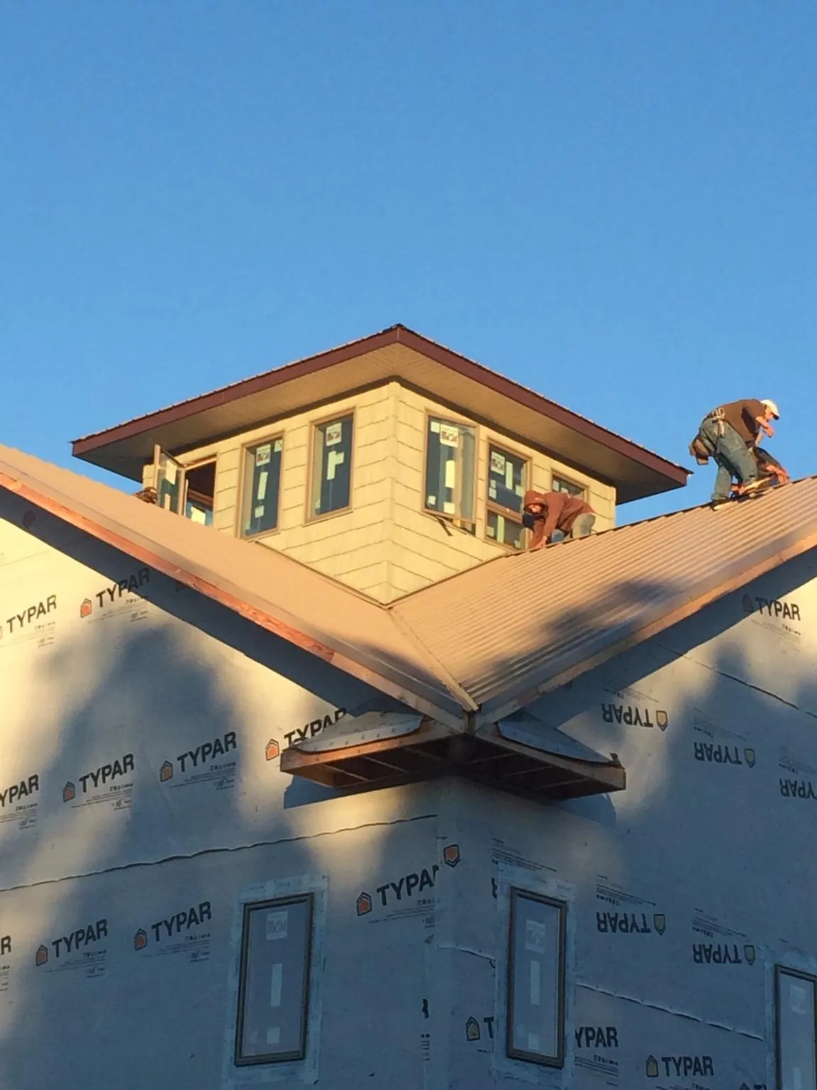 Roofers working around a rooftop cupola on a new metal roof at sunset — Roof Waterproofing in Fort Loudon by Roofing Brothers